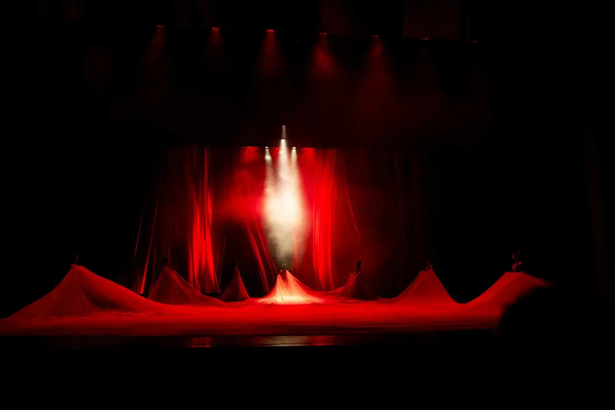 Stage with red curtains and fabric, lit by spotlights, creating a dramatic atmosphere.