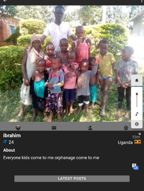 A man standing outdoors with a group of children of different ages in front of lush green bushes and trees.