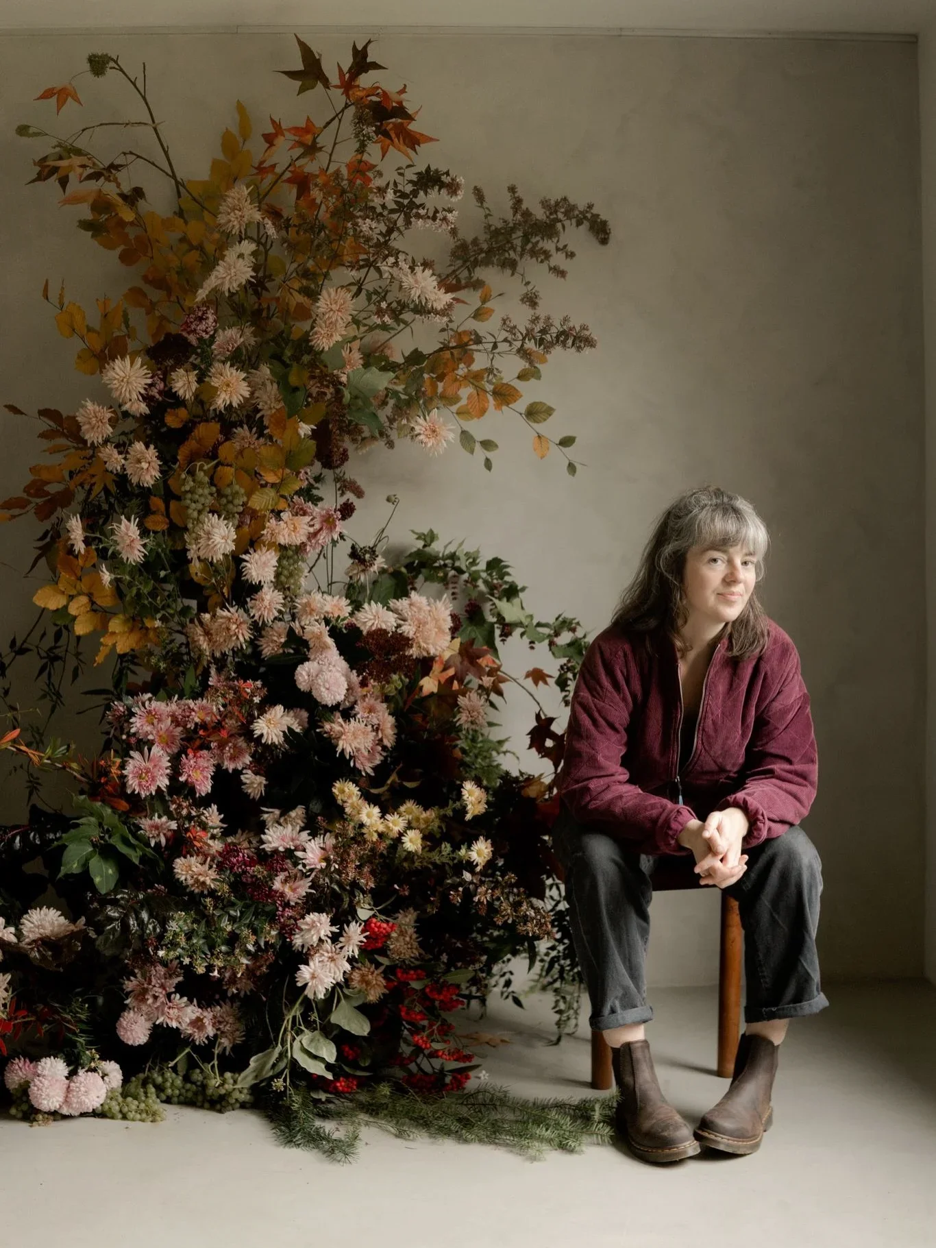 Portrait de l'artiste floral Freya Joy Garden Flowers assise dans un studio photo à côté d'une arche florale.