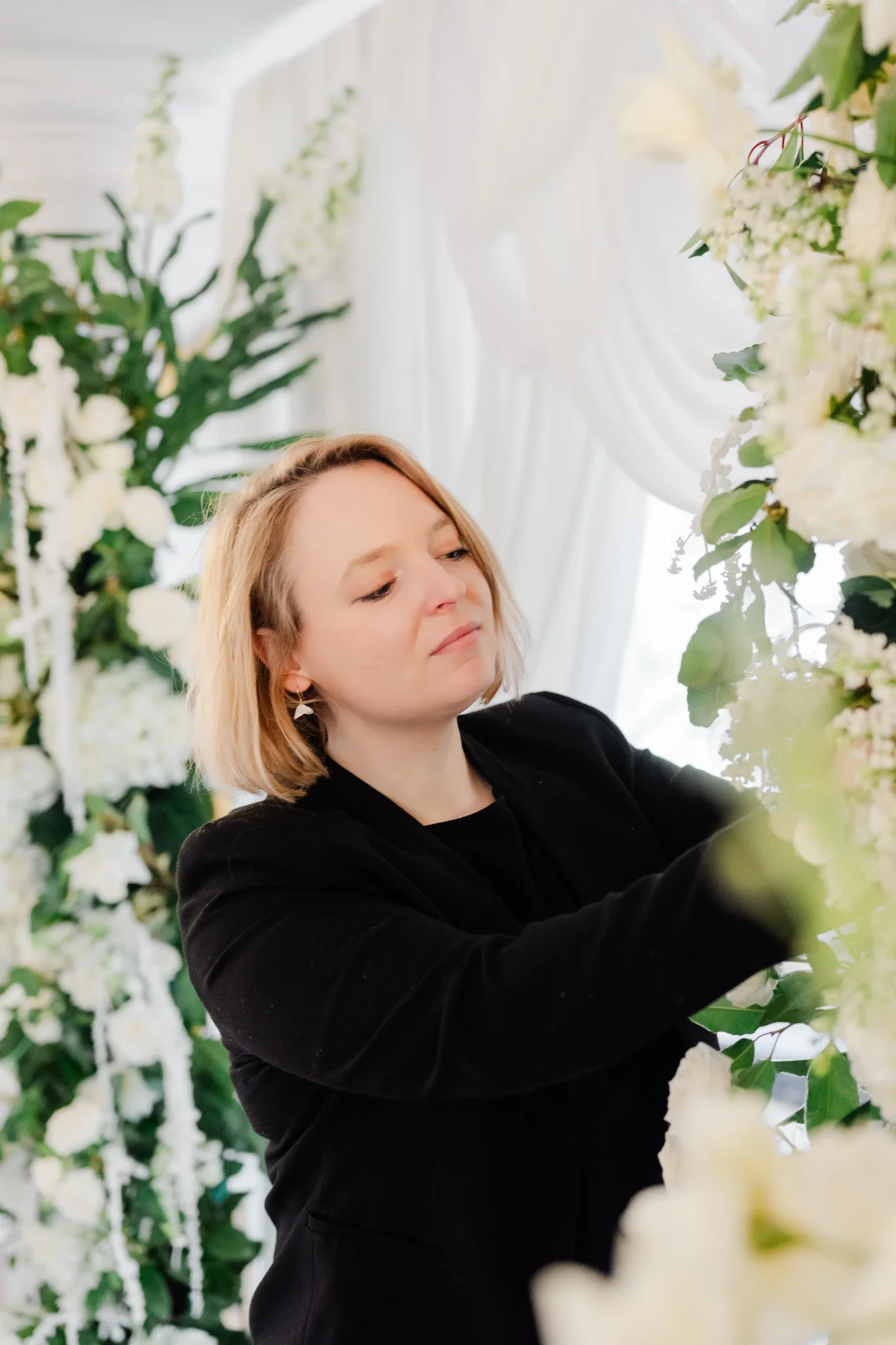 Portrait de la designer floral Vanessa de Vanessa Elven Flower entrain de fleurir une arche de cérémonie de mariage.