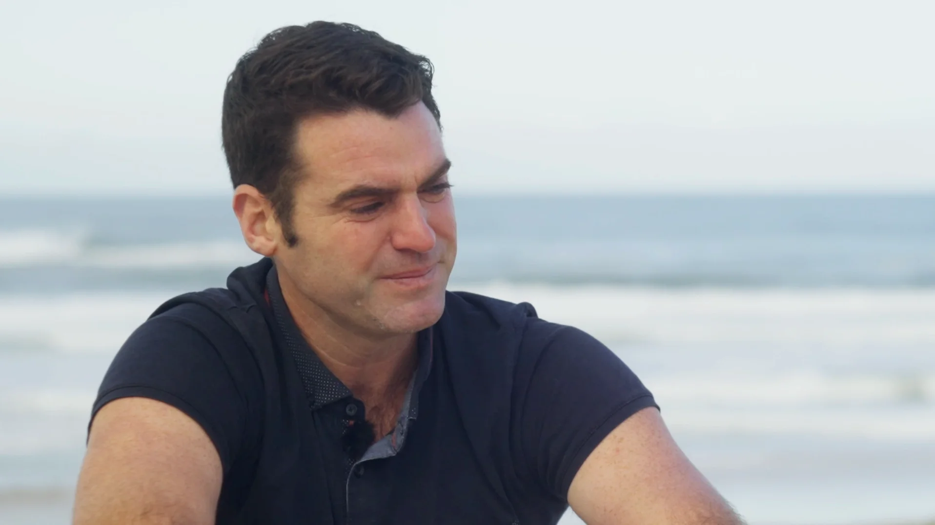 Portrait vidéo introspectif de Julien que l'on voit ému assis sur la plage pendant son interview.