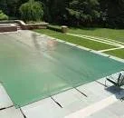 Piscine avec couverture verte dans un jardin.