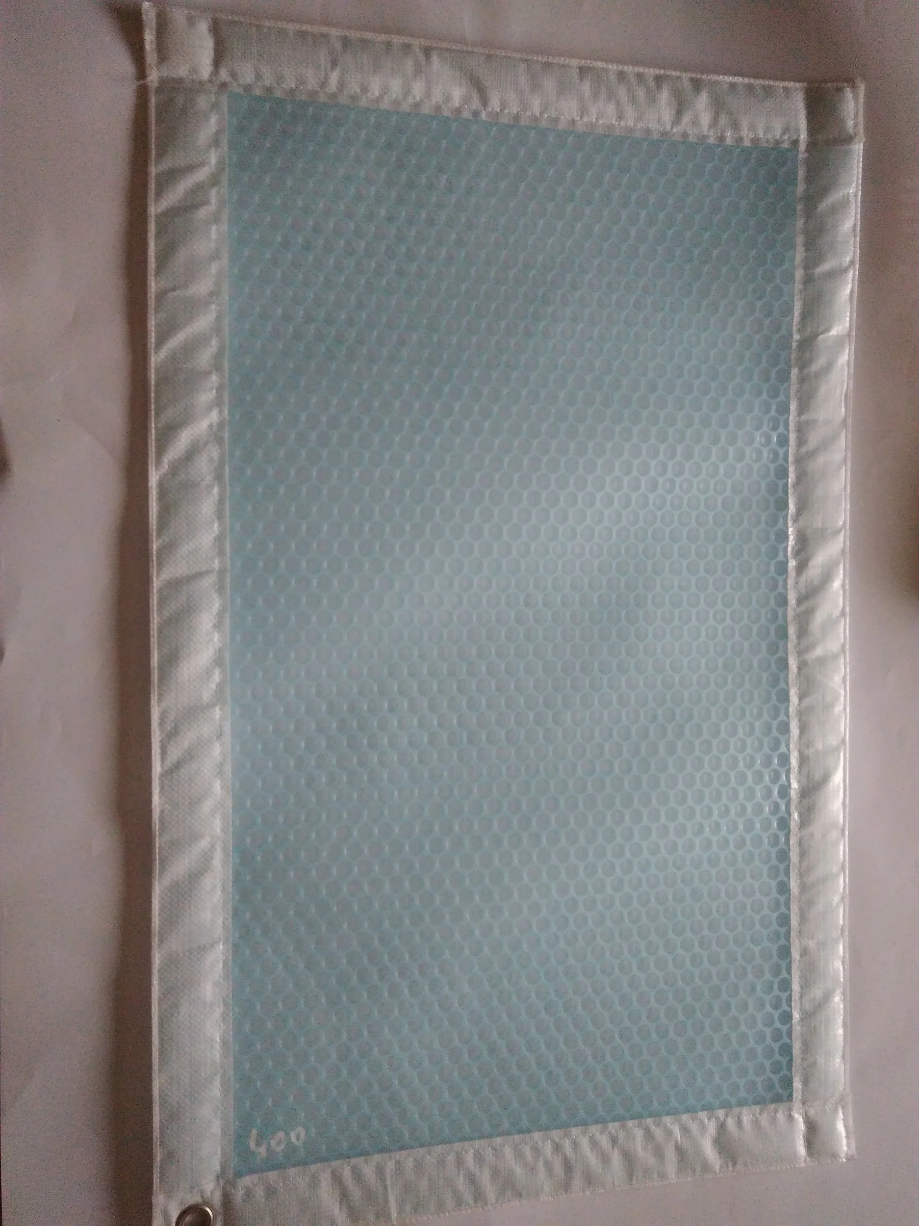 Tissu à motif hexagonal bleu avec bordure blanche, sur une surface blanche.