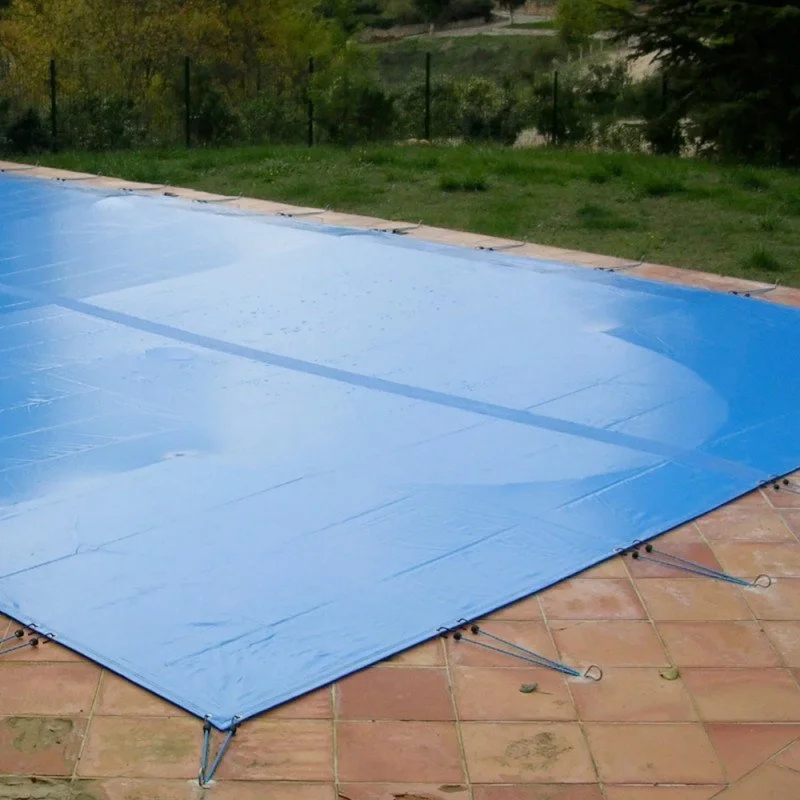 Couverture de piscine bleue sur une terrasse en carrelage.