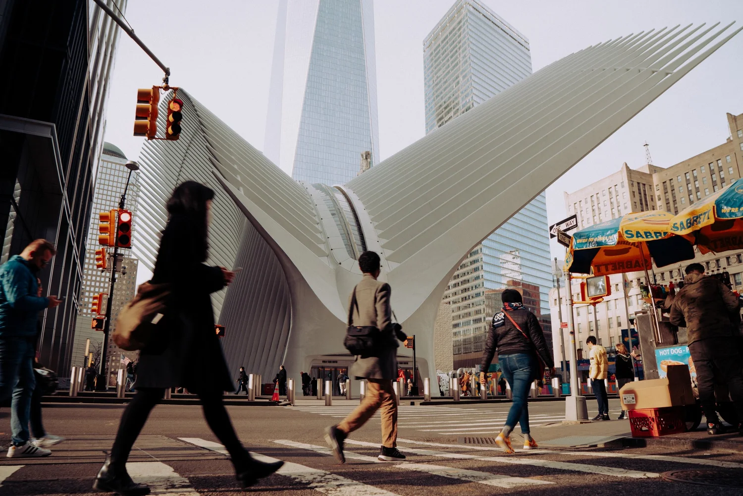 Commuters crossing in front of the white wings of the Oculus