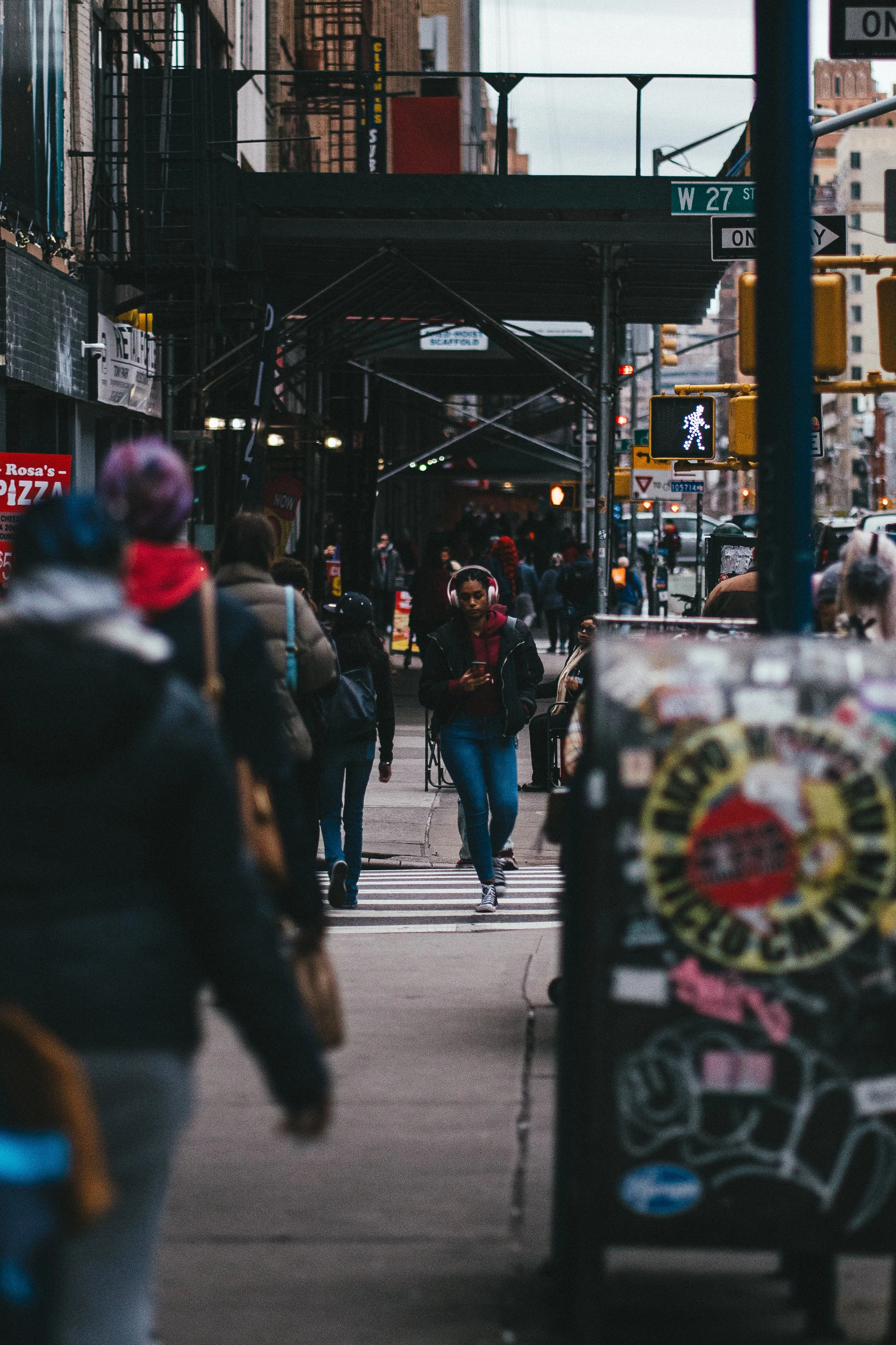 A woman walks down a busy New York City street as she checks her phone.