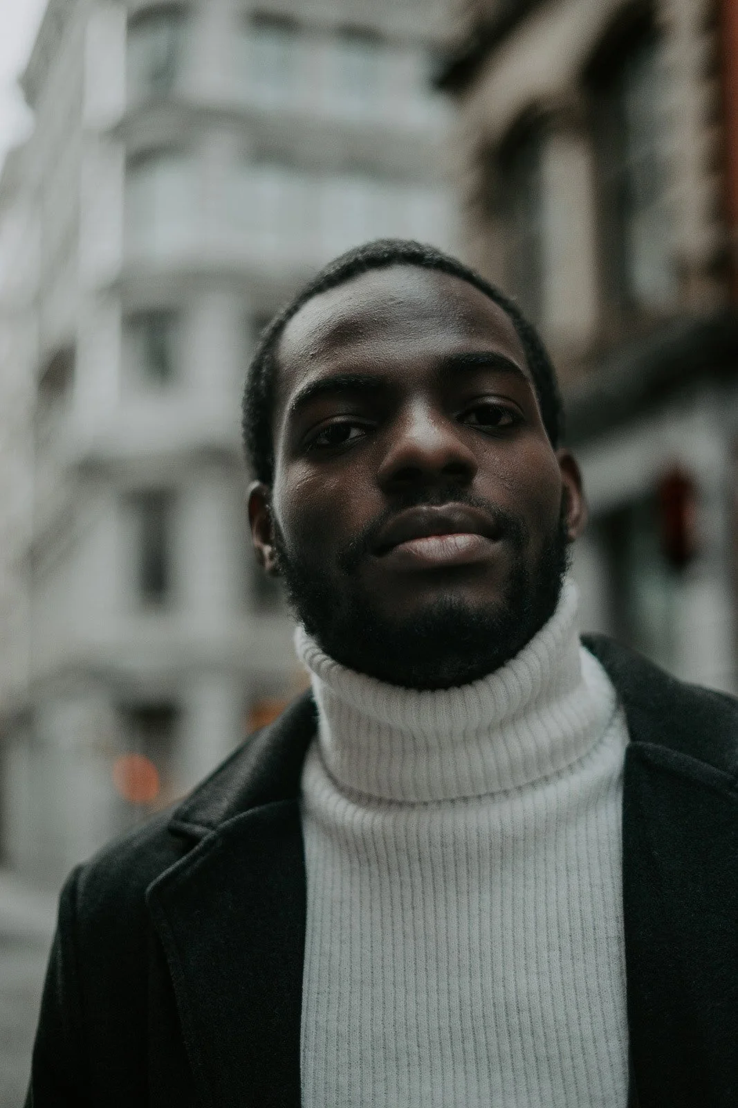 A well dressed man stands in the middle of Soho, New York City, with a look of longing on his face.