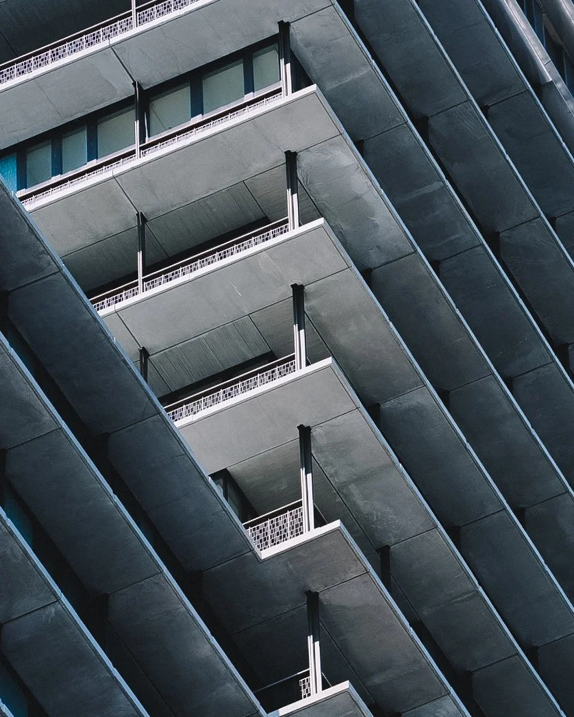 Close-up view of modern apartment building balconies with concrete and metal railings, seen from below.