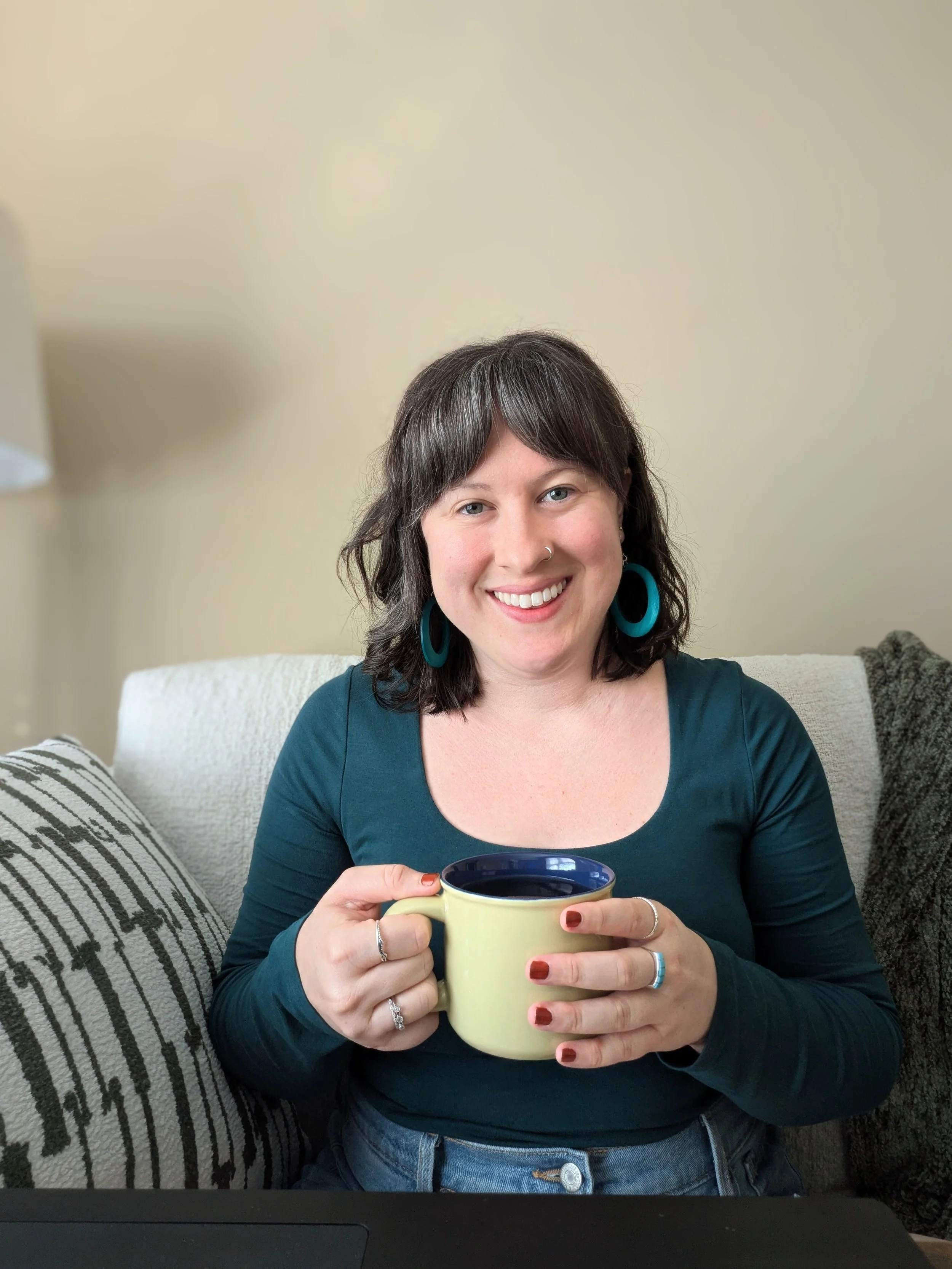 female therapist holding cup of tea sitting on therapy couch
