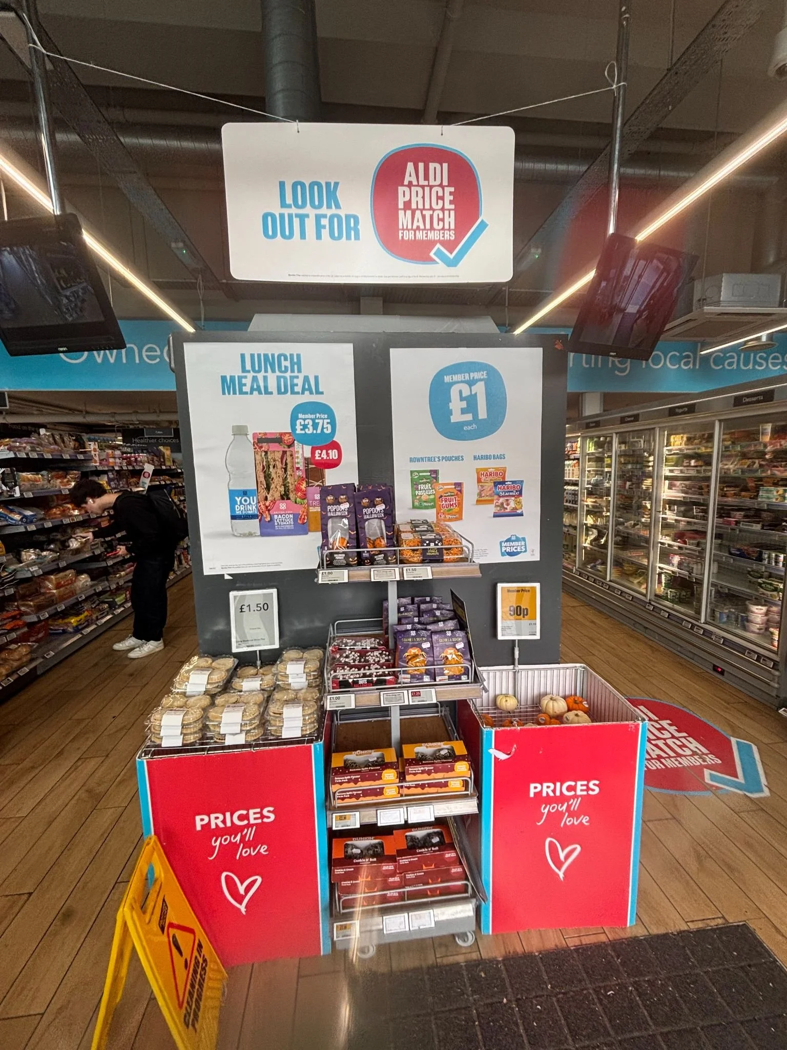 Display of discounted snacks and candies in a supermarket, with signs indicating prices and special offers for members at Aldi.