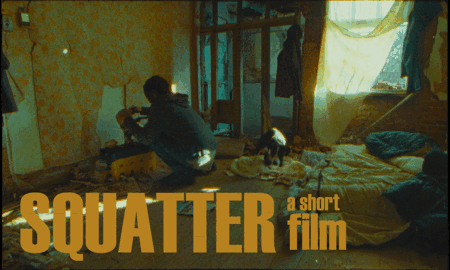 A person sitting on the floor in a cluttered room with a dog and cluttered bedding, sunlight coming through a window with yellow and green curtains. Text overlay reads 'SQUATTER a short film'.