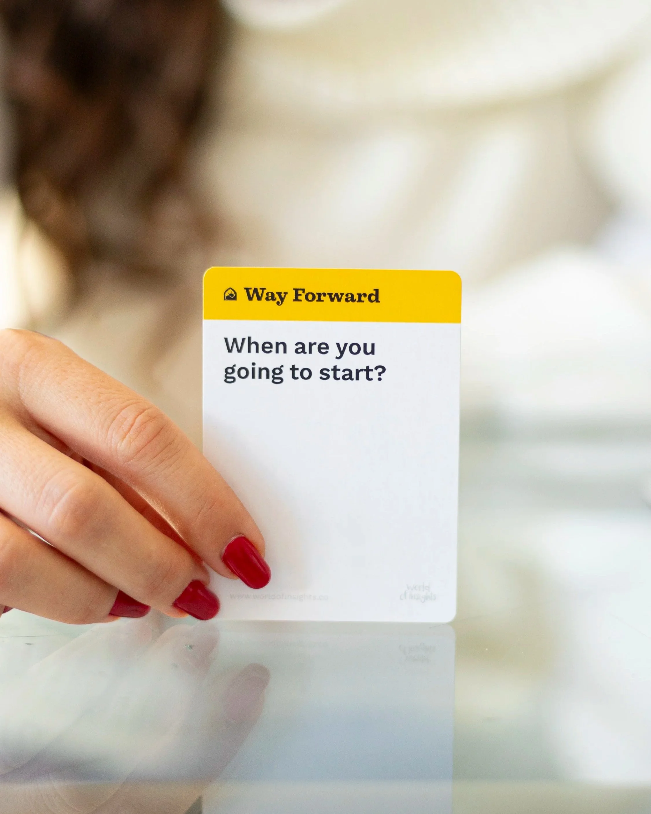 Close-up of a person with red nails holding a white card with a yellow header labeled 'Way Forward' and the question, 'When are you going to start?'