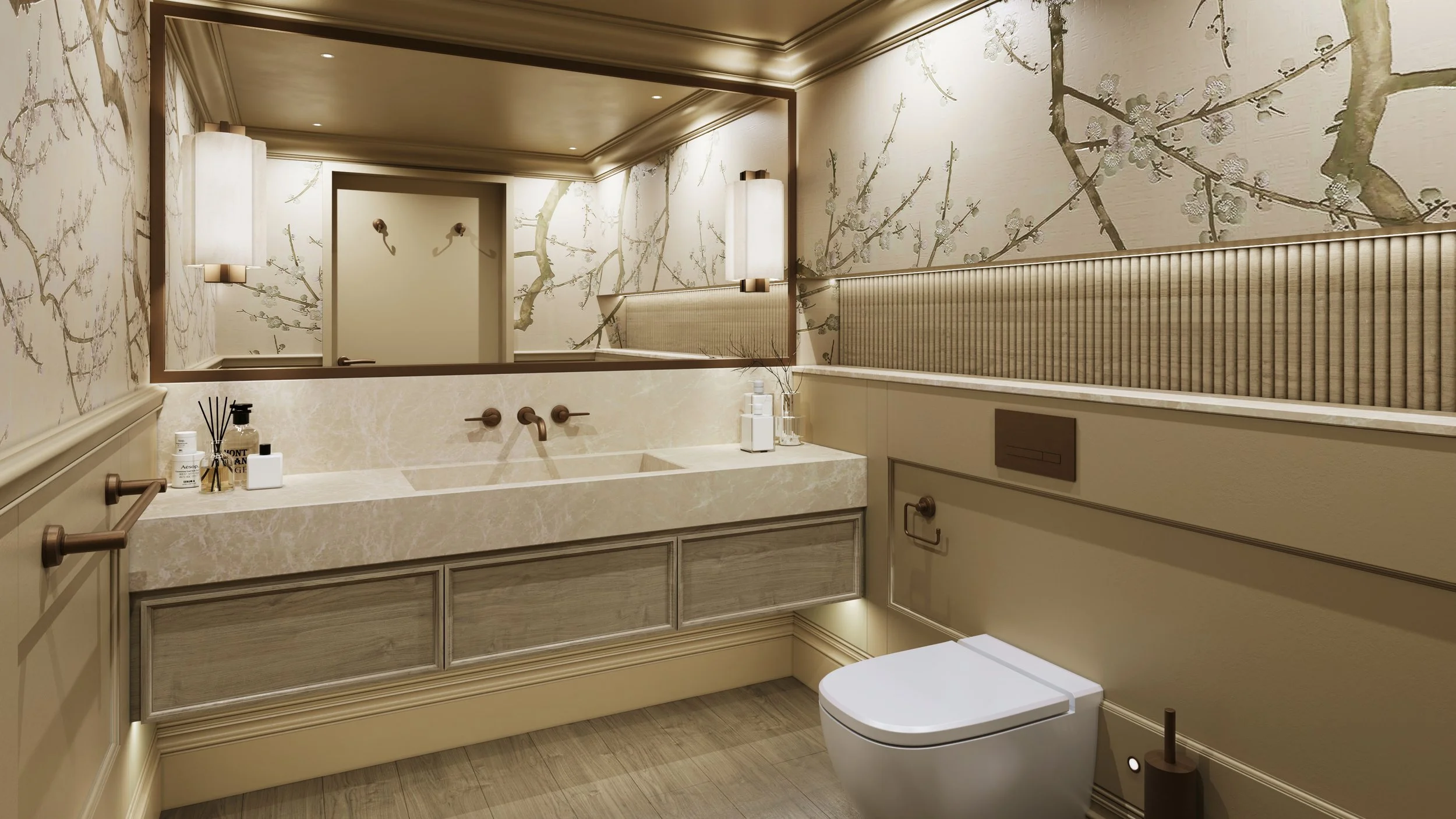 Luxury residential toilet interior featuring a large rectangular mirror with warm recessed lighting, marble sink vanity unit with grey oak drawer fronts, and wall-mounted bronze faucets. The walls are decorated with beige botanical wallpaper showcasi