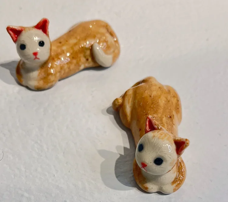 Two tiny figurines of cats.