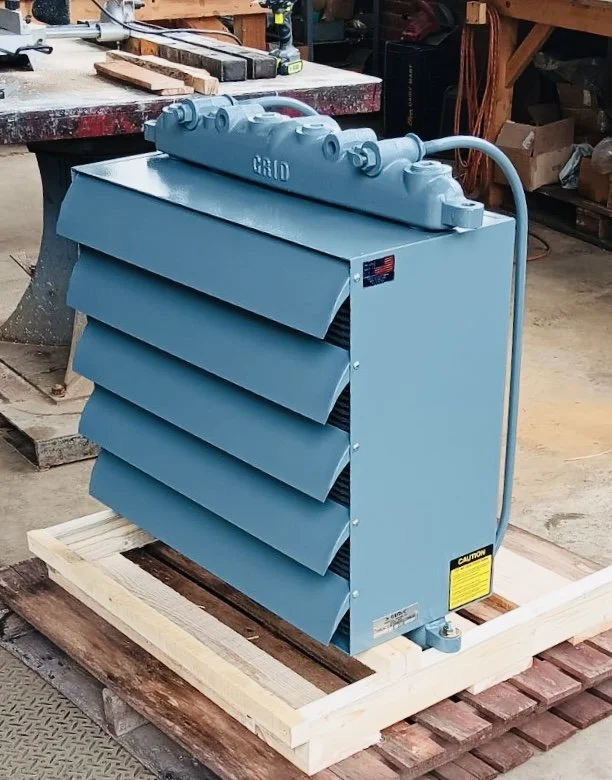 Blue industrial air filter or air compressor component with louvers, placed on wooden platform in workshop.