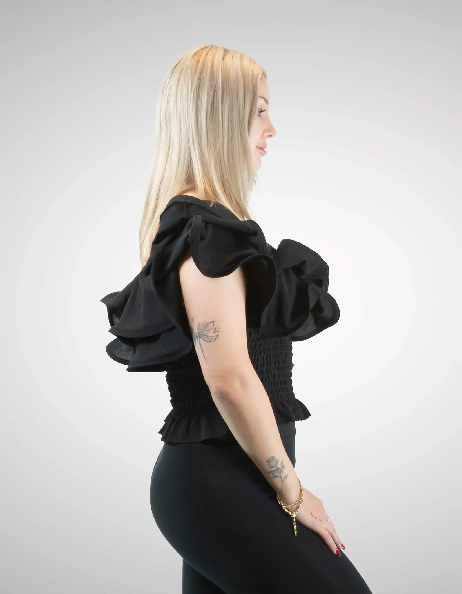 Model trägt schwarzes Volanttop Seite.