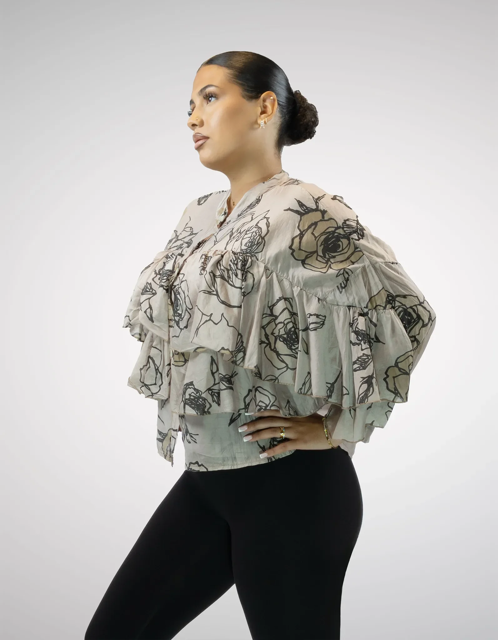 Modell trägt taupefarbene Bluse mit Blumenprint und Rüschen.