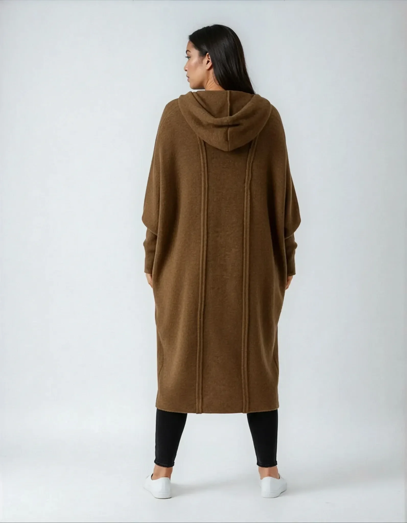 Model trägt braunen Strickmantel Rücken.