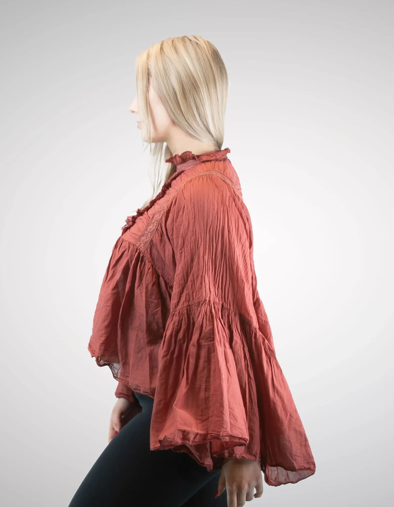Seitliche Vorderansicht der rostroten Damenbluse im Boho-Stil mit hochgeschlossenem Rüschenkragen und fließendem Stoff.