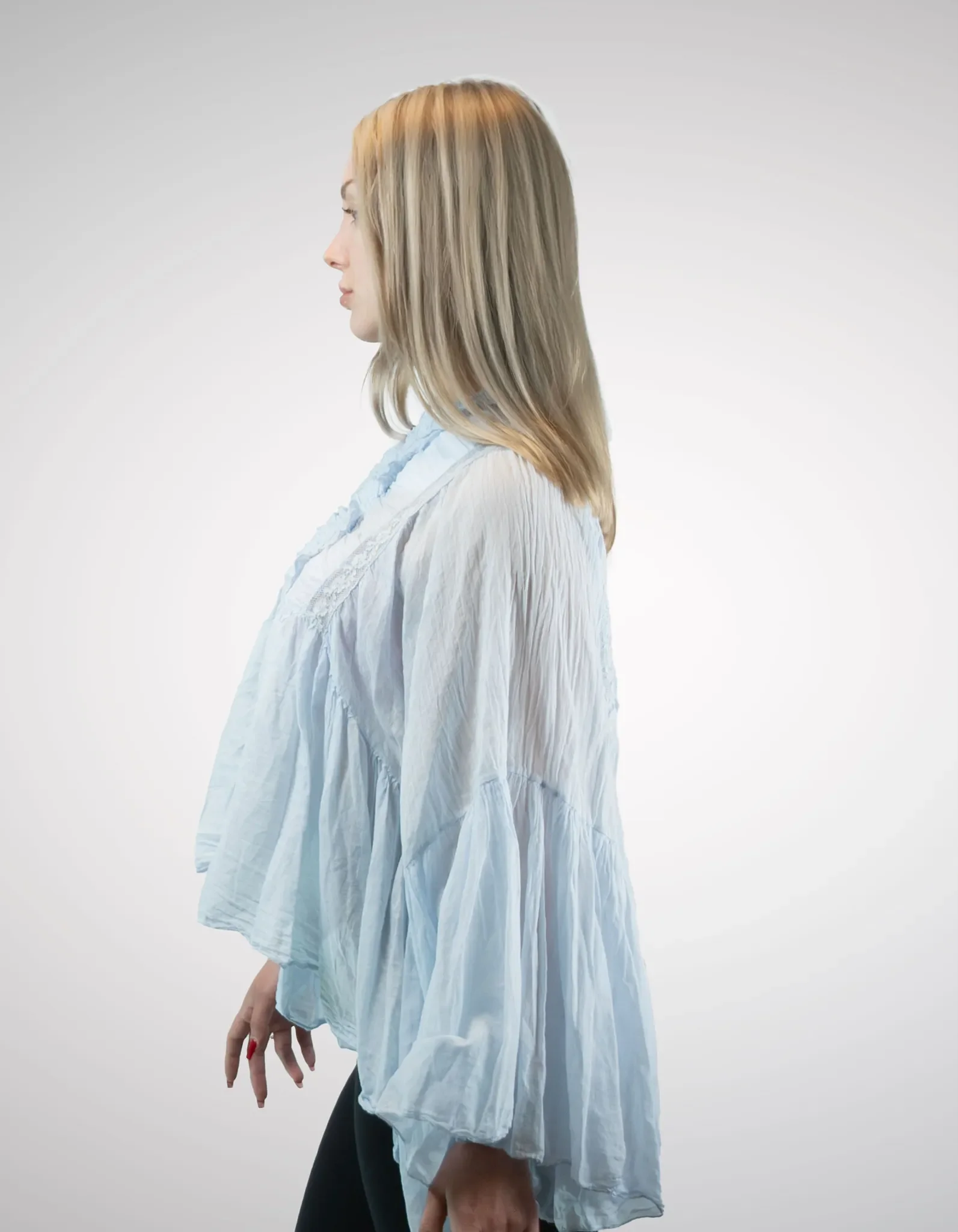 Profilansicht der hellblauen Damenbluse im Boho-Stil, die den weiten Fall der Schluppenärmel und den fließenden, gestuften Stoff zeigt.