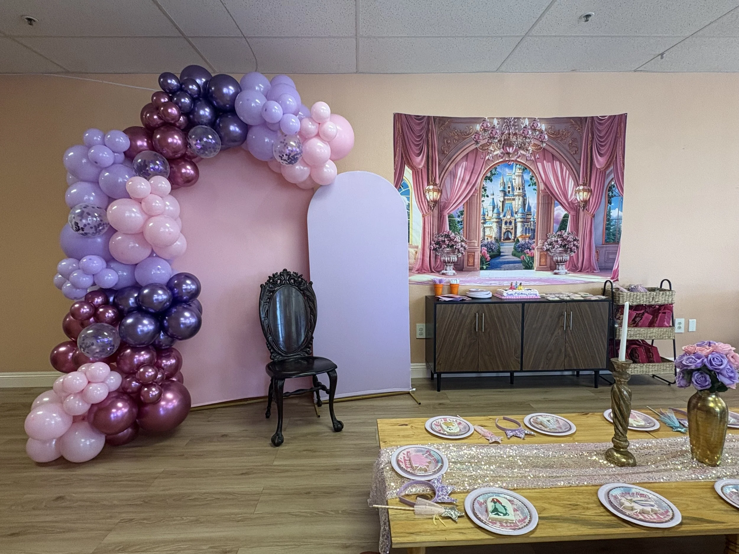 Whimsical kids’ birthday party setup with balloon garland, throne chair, and themed table at Kindred Play Collective in Orangevale.