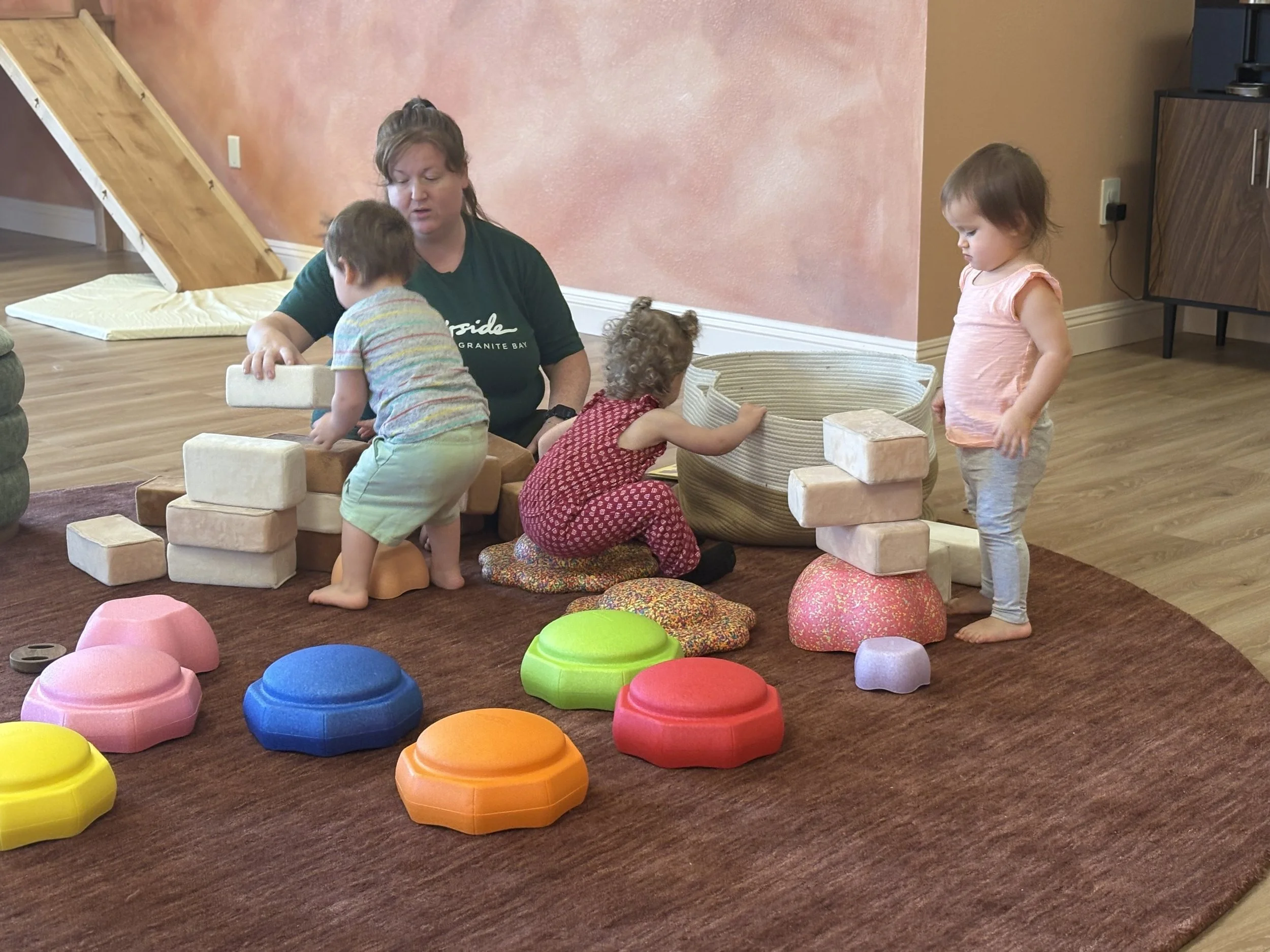 Toddlers playing with wooden blocks and colorful stepping stones at Kindred Play Collective indoor playground in Orangevale.