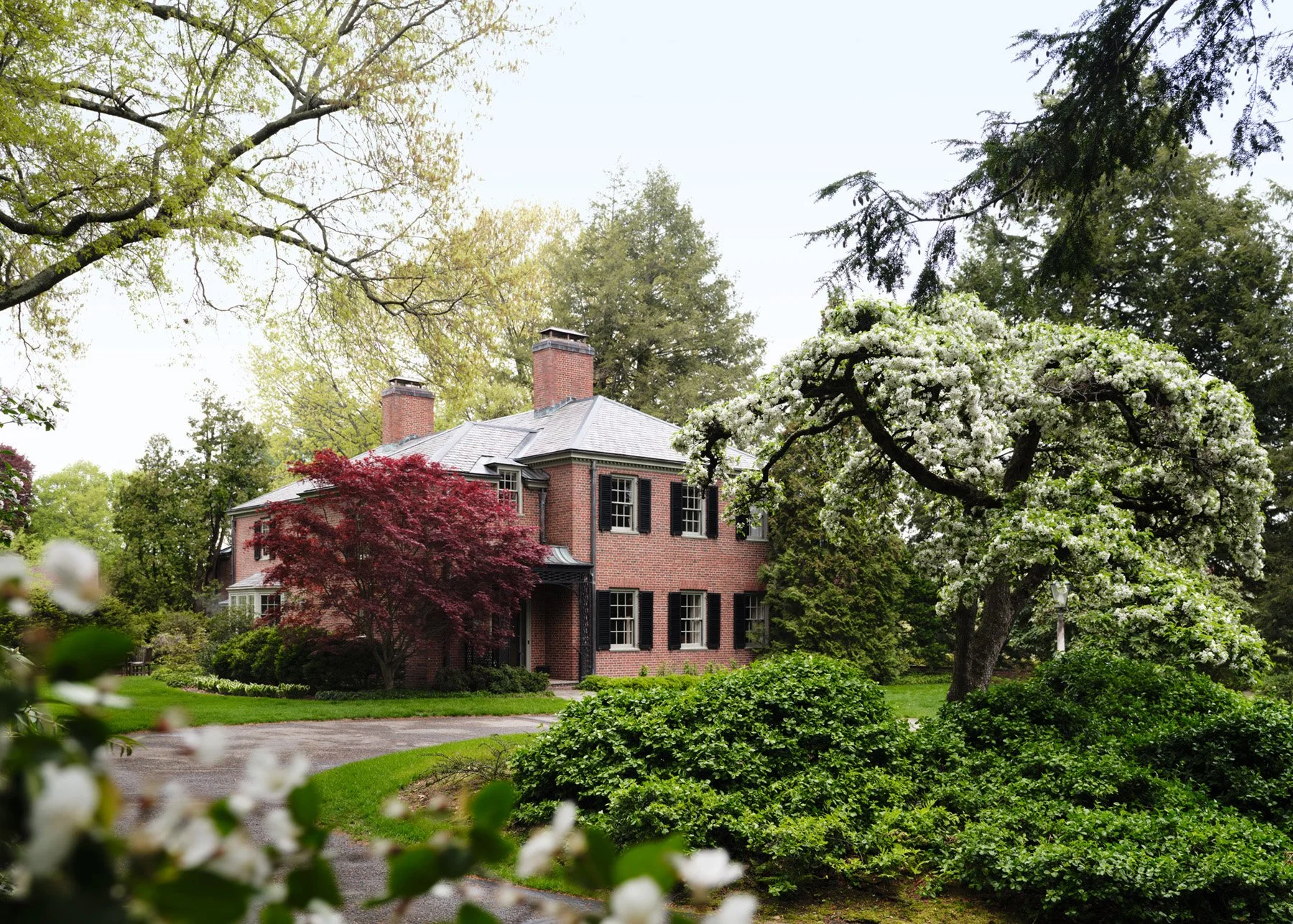 SACRIS Interior Architecture & Design renovation of a 1937 brick Georgian Revival estate with slate roof, black shutters and flowering crabapple, Nashua New Hampshire