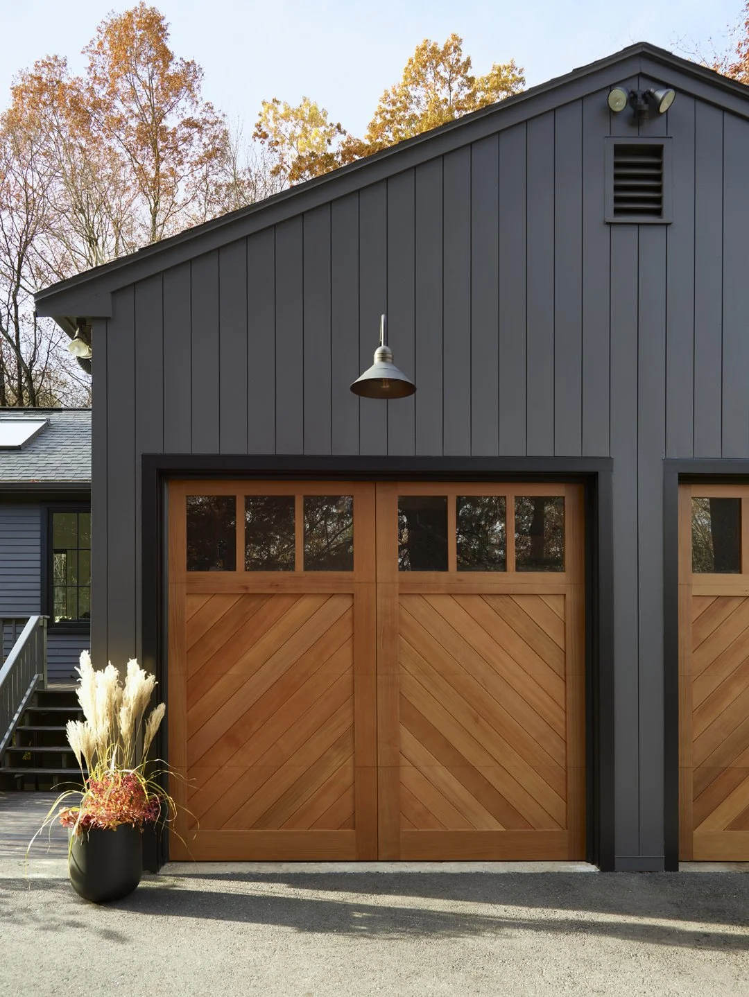Sacris Design charcoal exterior vertical siding with cedar chevron garage doors, serving mountain and lakes region New Hampshire, Maine and North Shore Massachusetts
