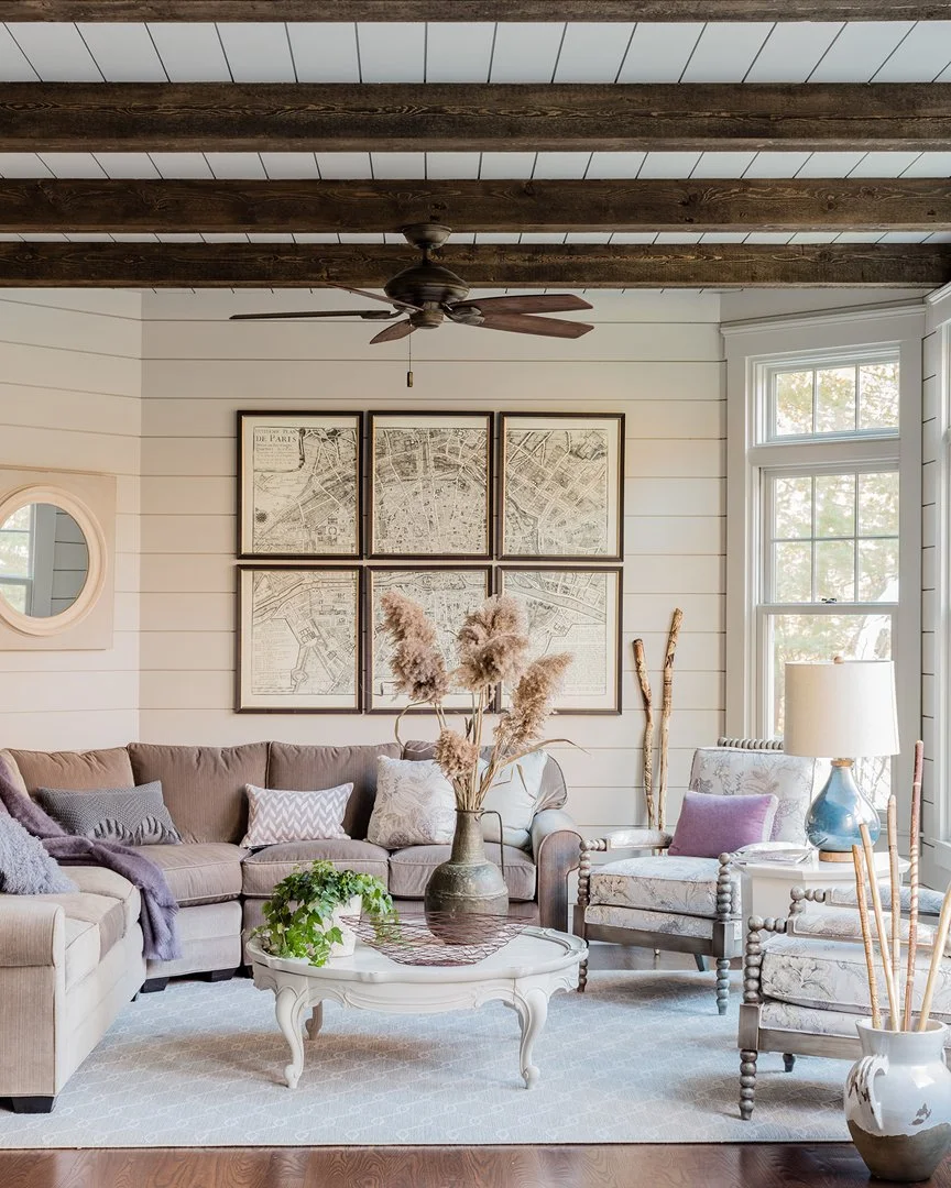 Casual living room with shiplap walls, dark wood beam ceiling, vintage Paris map art gallery wall, and bobbin leg accent chairs — full service interior design by SACRIS Interior Architecture & Design, North Shore Massachusetts