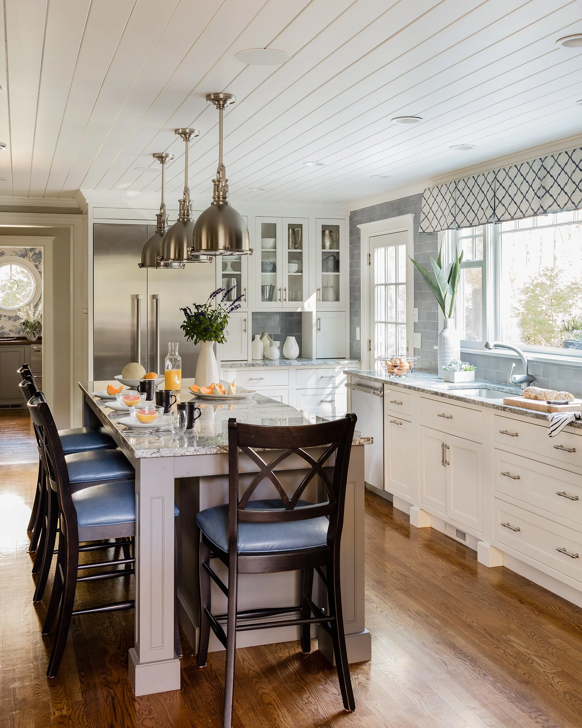 Luxury kitchen with beadboard ceiling, cream shaker cabinetry, nickel dome pendant lights, gray island, and blue leather barstools — full service kitchen design in Boxford MA by Sacris Design