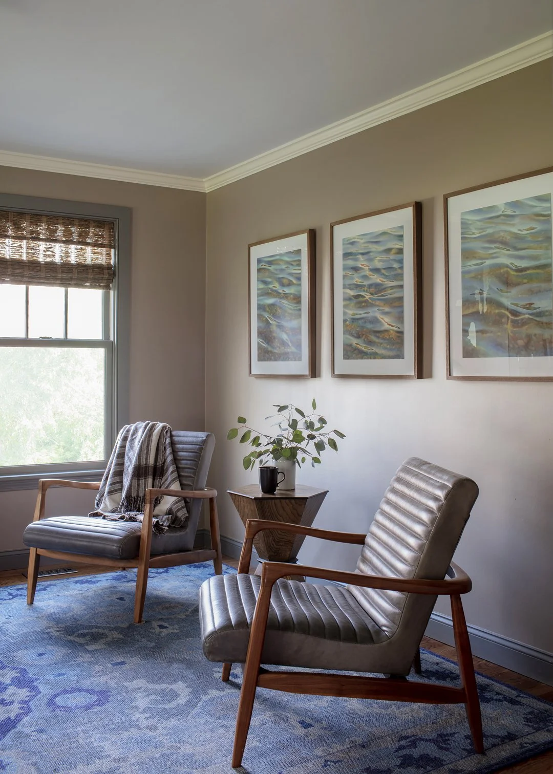 Home office sitting area with mid-century leather channel chairs, blue patterned wool rug, and water photograph triptych — luxury interior design in Essex County MA by Sacris Design