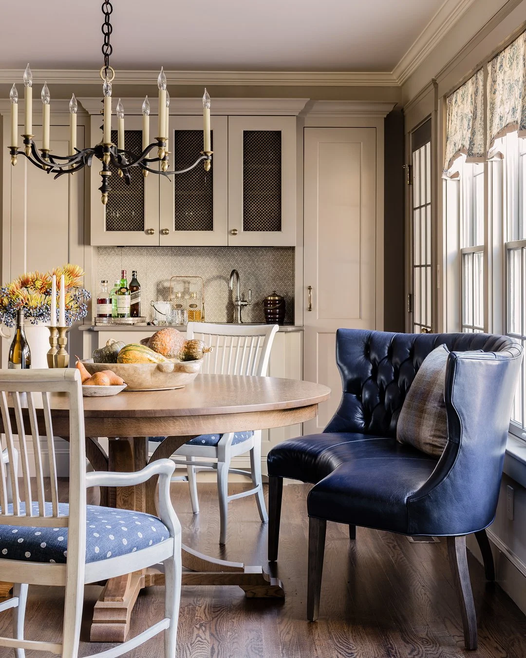 Traditional breakfast nook with navy tufted leather dining chair and custom built-in bar cabinetry — luxury interior design north of Boston by Sacris Design