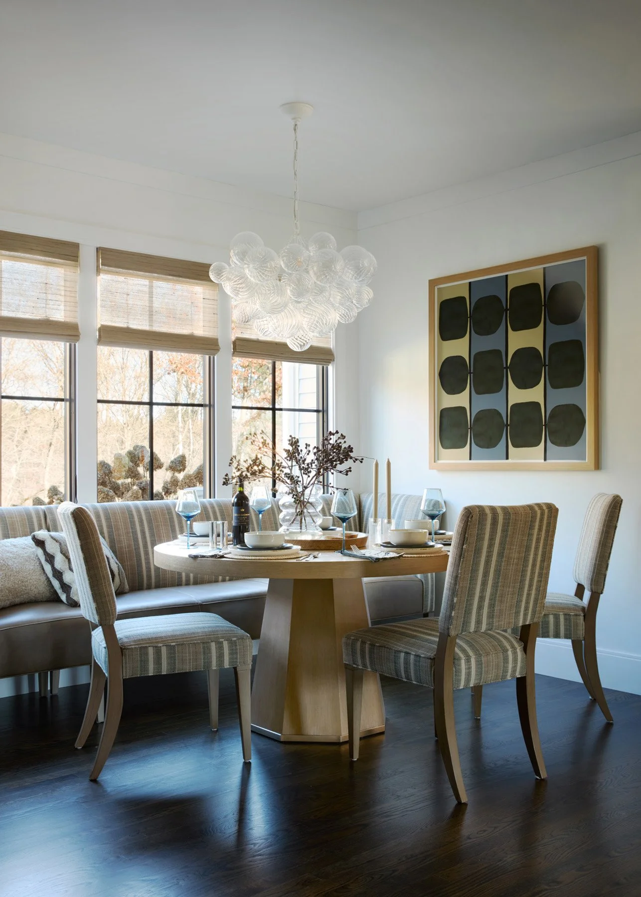 SACRIS breakfast area with custom Wesley Hall banquette, Hickory White ash pedestal table, Visual Comfort chandelier and woven natural shades, North Andover Massachusetts