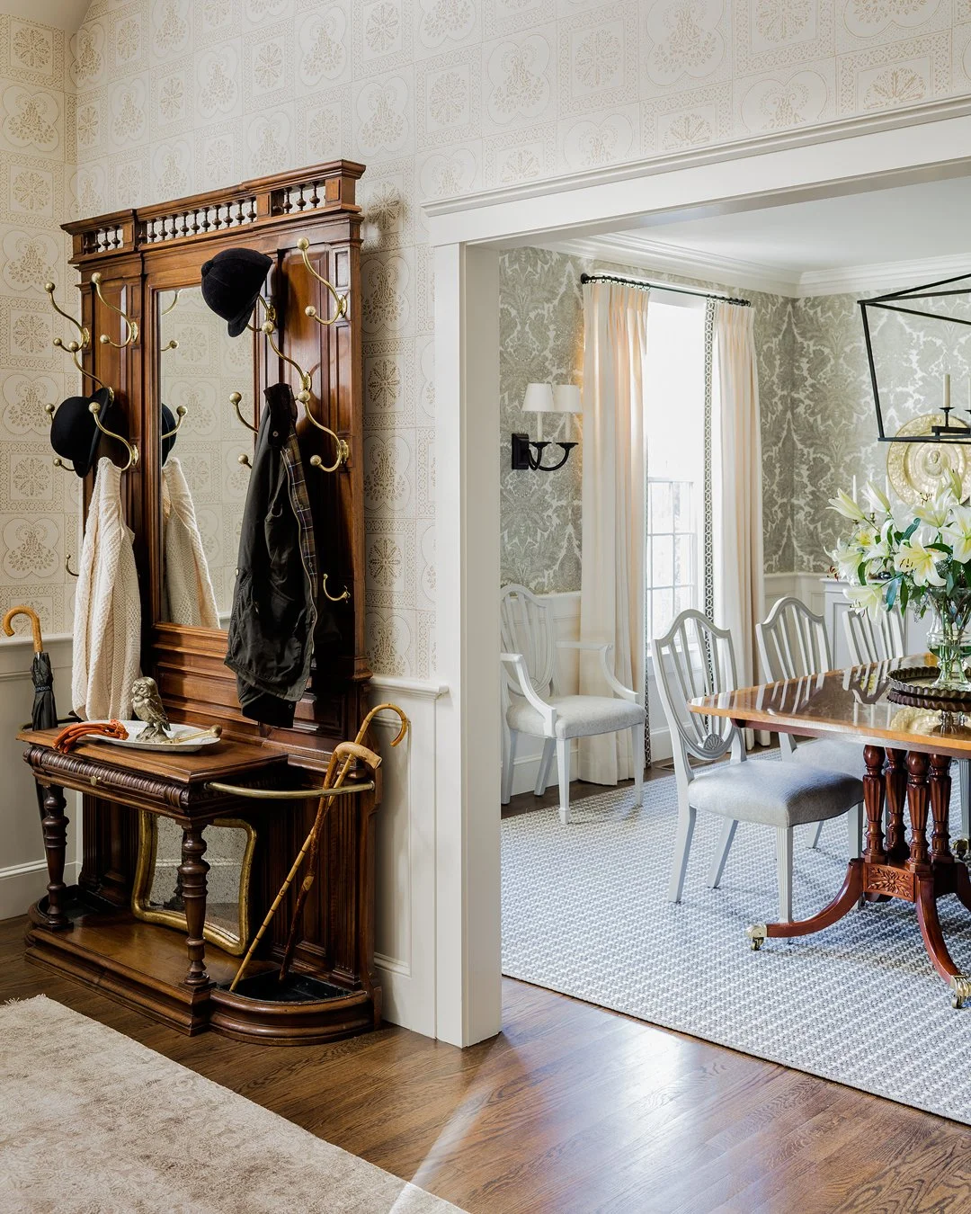 Entry hall with antique hall tree, brass coat hooks, and open view into formal dining room — luxury traditional home interior design in Essex County MA by Sacris Design