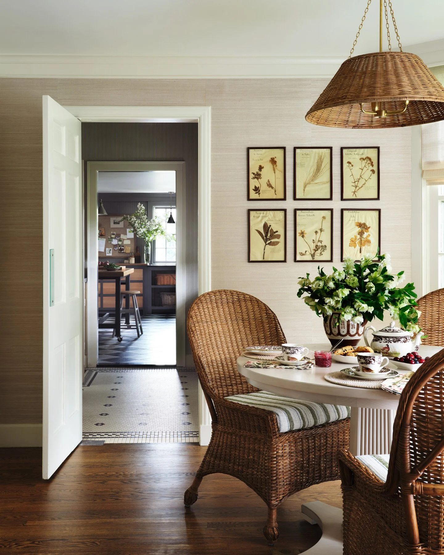 SACRIS breakfast room with wicker chairs, framed antique botanicals and a view through the butler pantry to the Project Studio, Nashua New Hampshire