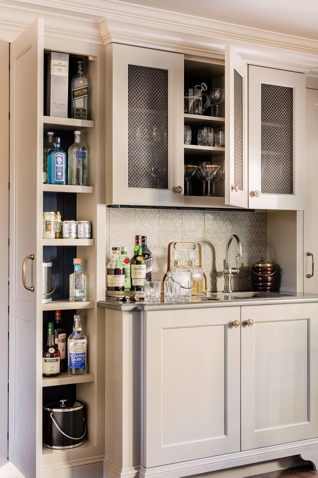 Custom built-in wet bar with cream cabinetry, brass mesh cabinet doors, and patterned tile backsplash — luxury home interior design on the North Shore of Massachusetts by Sacris Design