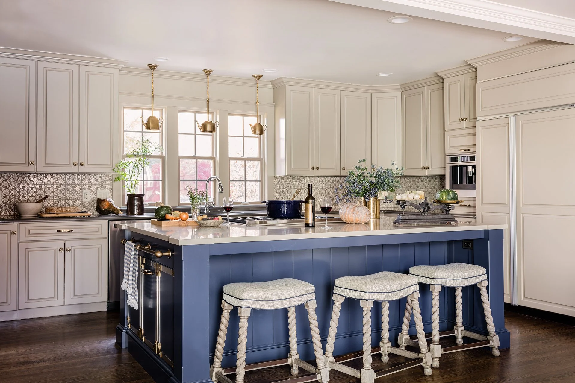 Luxury kitchen with blue island, barley twist barstools, warm white raised panel cabinetry, and brass teapot pendant lights — full service kitchen design in Essex County MA by Sacris Design