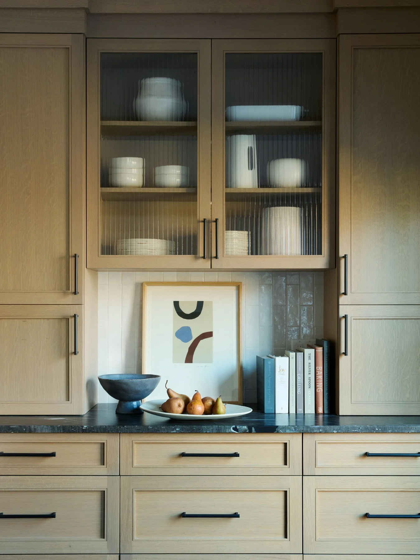 SACRIS white oak dish wall with reeded glass cabinet doors, leathered black stone countertop and vertical stack tile backsplash, North Andover Massachusetts