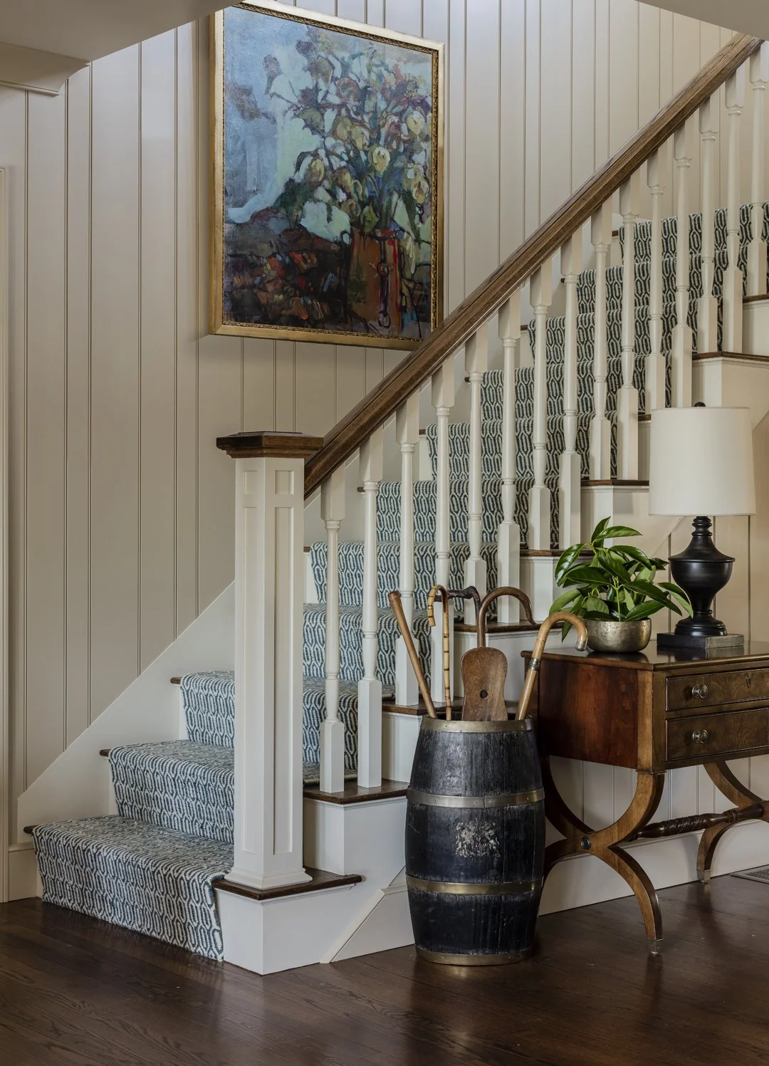 Traditional entry staircase with patterned wool runner, beadboard paneling, antique barrel umbrella stand, and oil painting — full service interior design by SACRIS, serving the North Shore of Massachusetts and New Hampshire