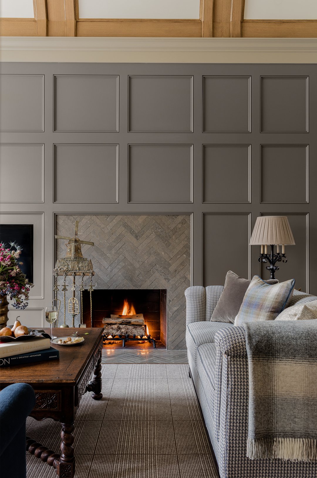 Living room with a custom herringbone limestone fireplace integrated into a panelled millwork wall.