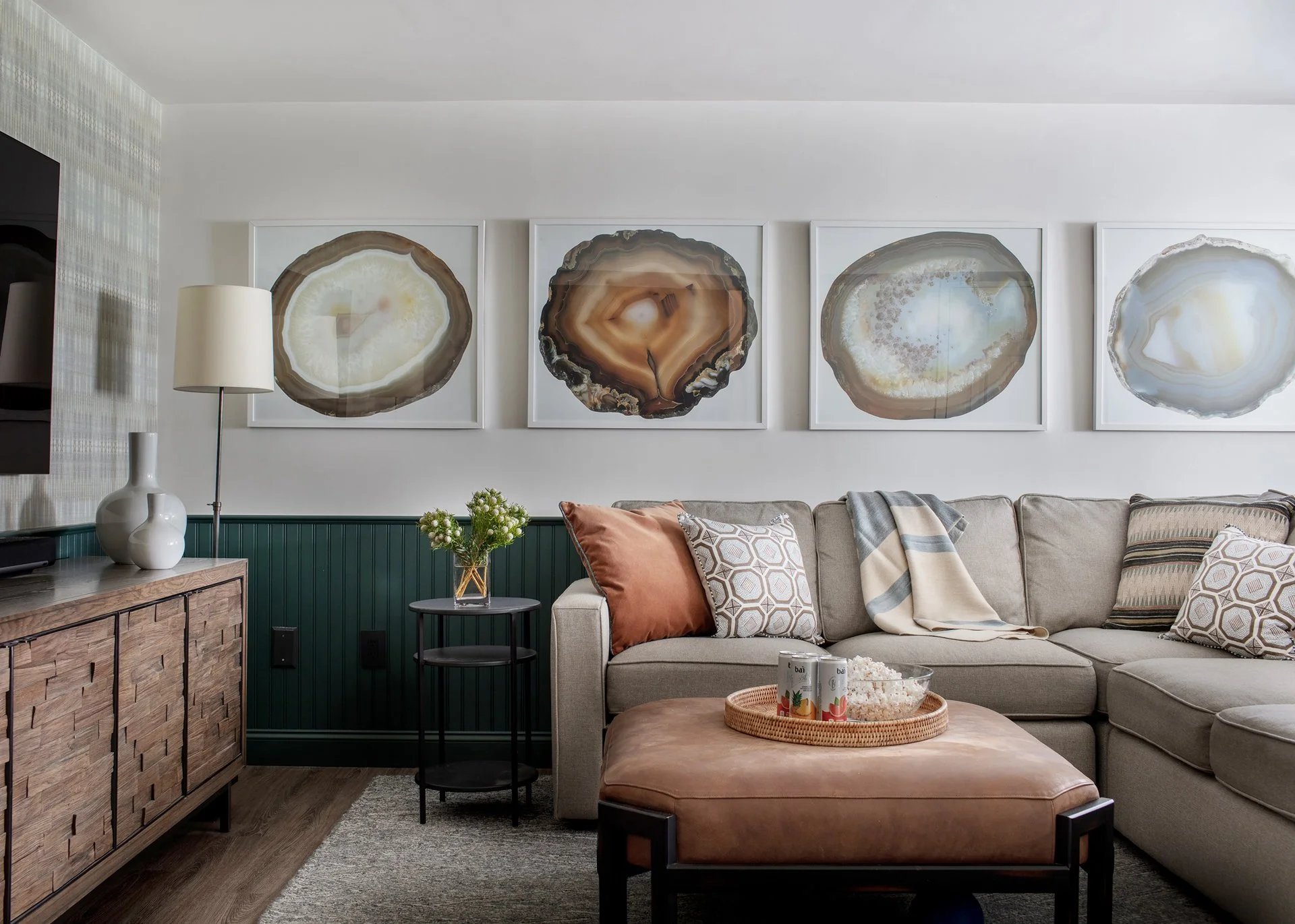 Family media room with dark green beadboard wainscoting, patterned grasscloth, leather ottoman and agate art— full service interior design in Boxford Massachusetts by Sacris Design