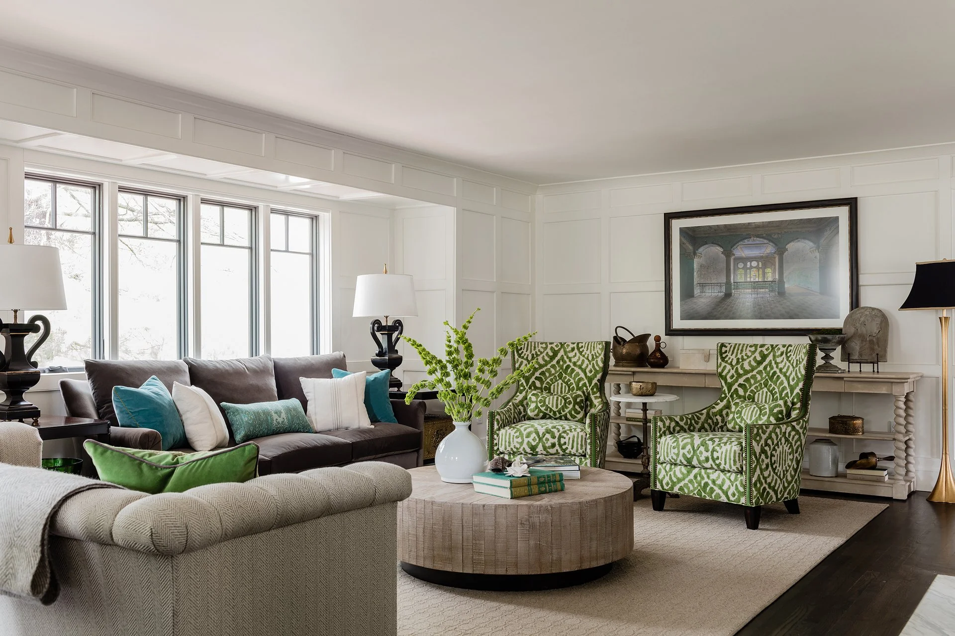 Living room with white panelled walls, colorful green ikat upholstered chairs, antiques