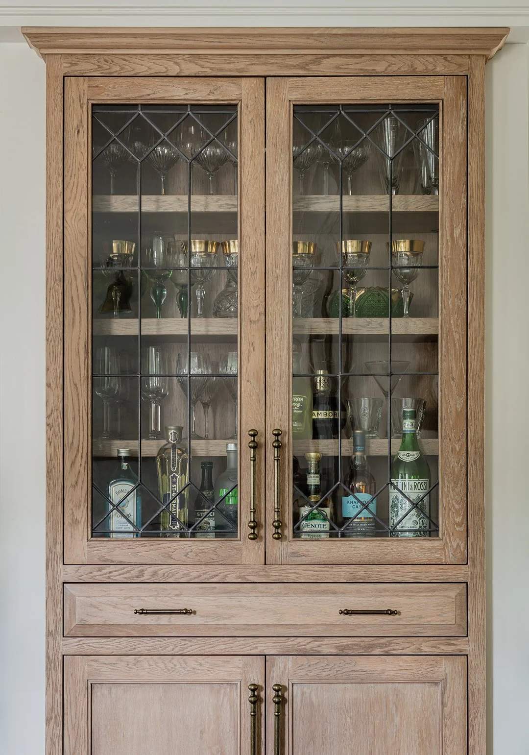 Sacris Design custom white oak bar cabinet with leaded glass doors and brass hardware, serving Ogunquit Maine and North Shore Massachusetts