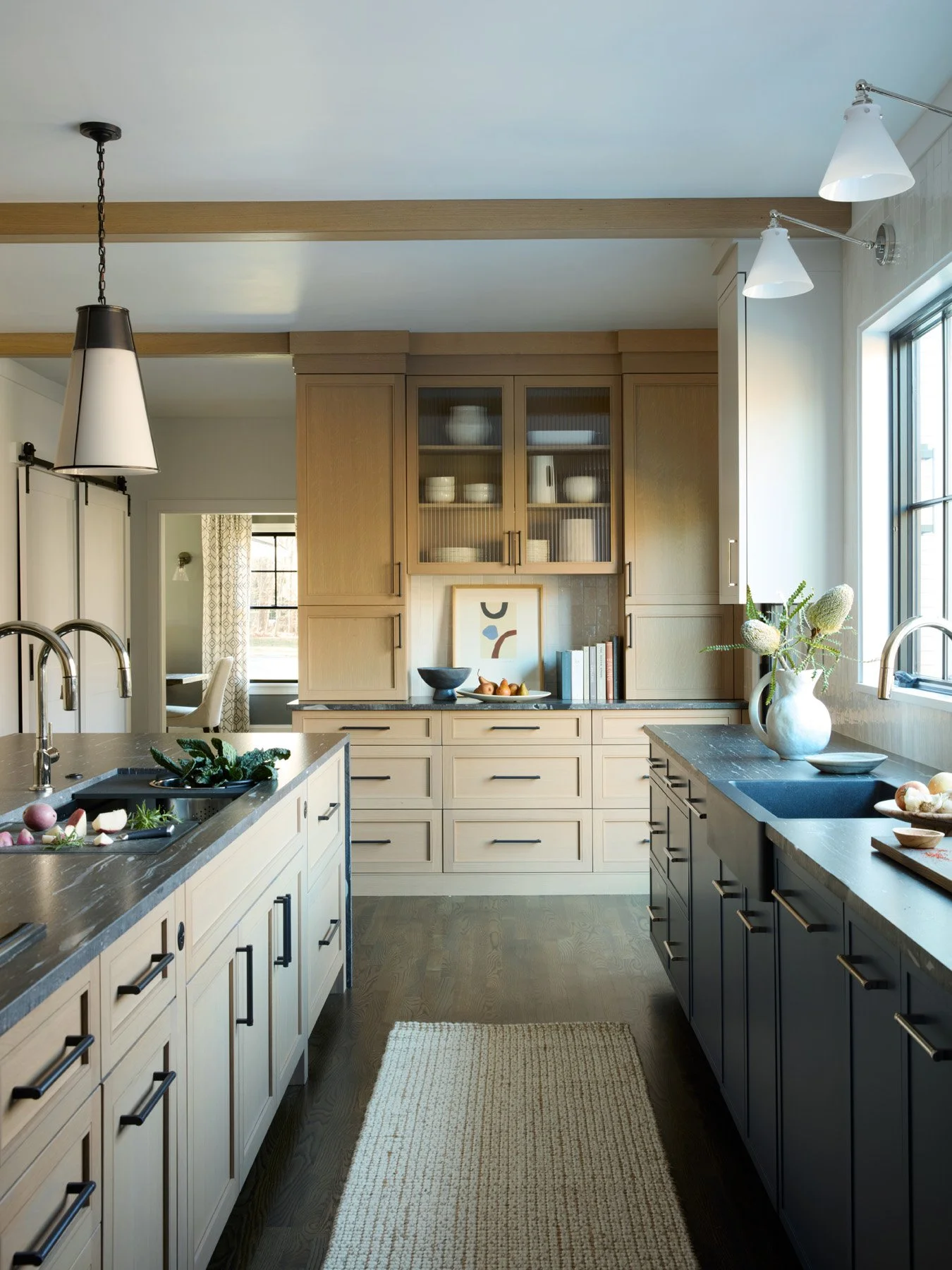 SACRIS kitchen with Galley workstation sink, white oak ceiling beams, reeded glass upper cabinetry and dual pull-down faucets, North Andover Massachusetts