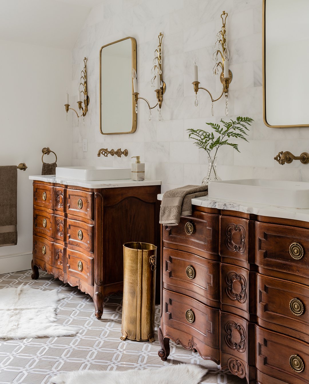 Elegant bathroom with vintage wooden vanities, custom curved marble countertops, antique brass  sconces and Phyllrich brass faucets