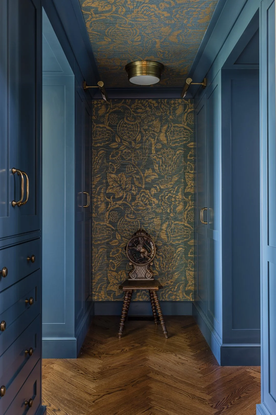 Luxury dressing room with peacock blue painted built-in cabinetry, gold and blue grasscloth wallcovering, herringbone wood floor, and brass hardware — full service interior architecture on the North Shore of Massachusetts by Sacris Design