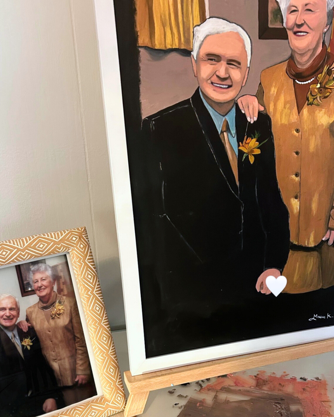 A framed photo of an elderly man and woman smiling and standing close together, with the woman placing her hand on the man's shoulder.
