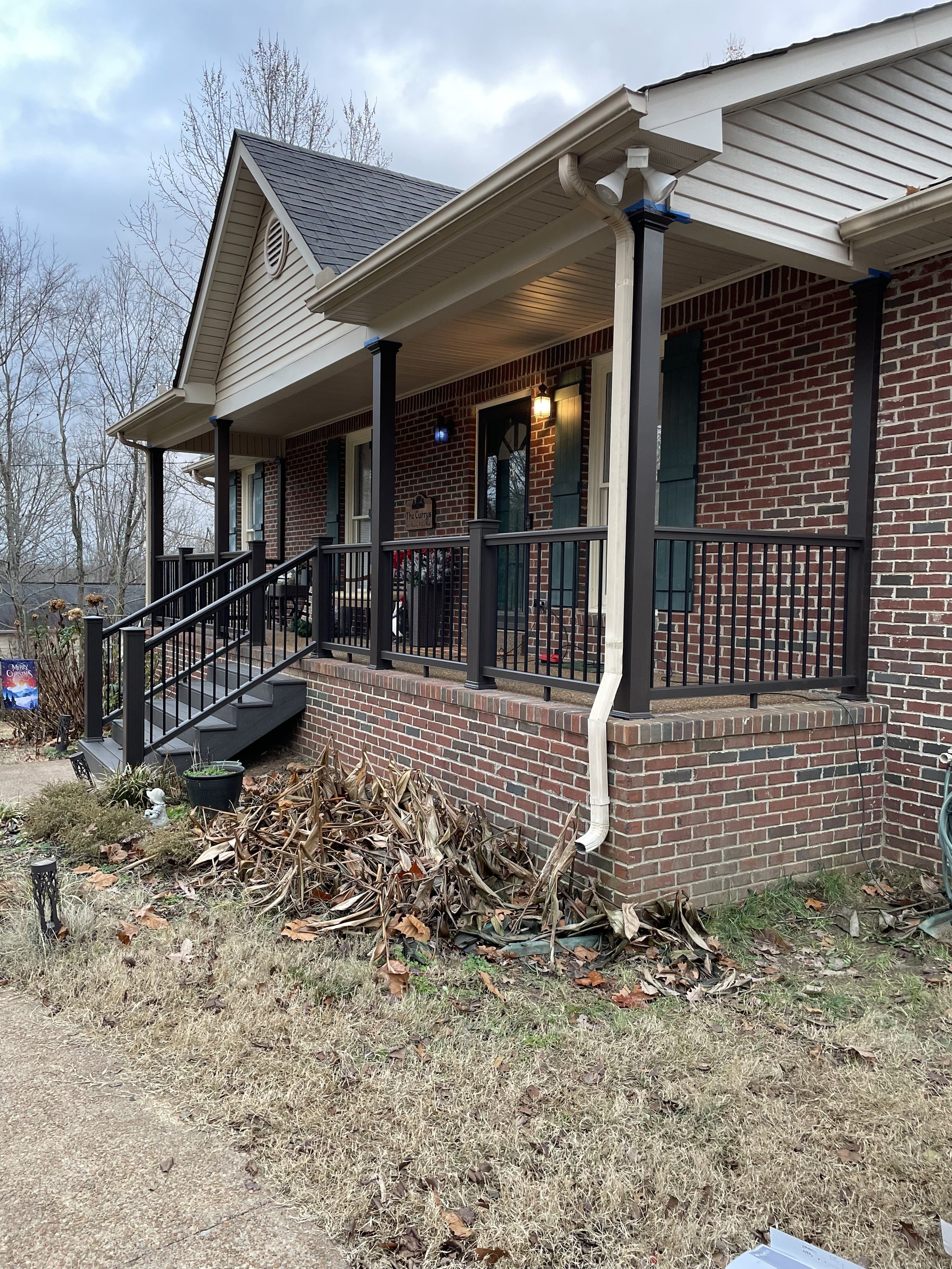 Front porch of a brick house upgraded with low maintenance composite decking and composite railings installed with aluminum balusters. A great investment for a long lasting high quality home upgrade.