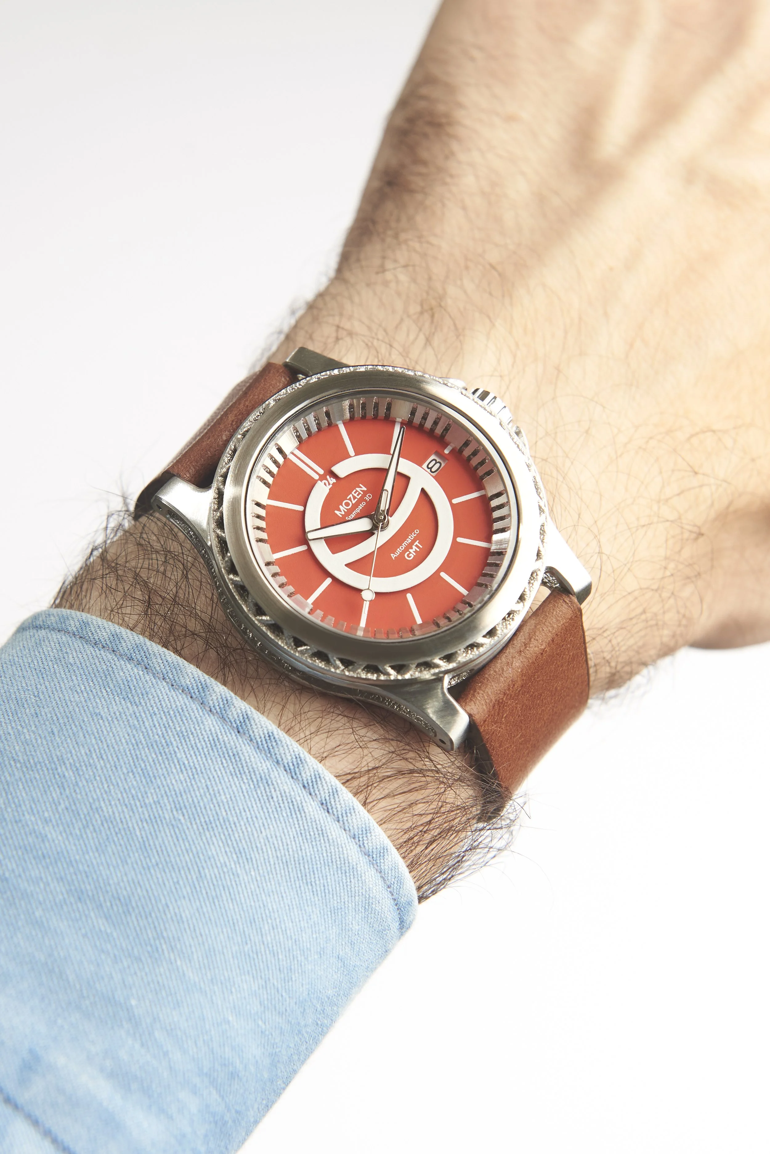 A person's wrist wearing a Mozen GMT wristwatch with an orange dial and a brown leather strap.