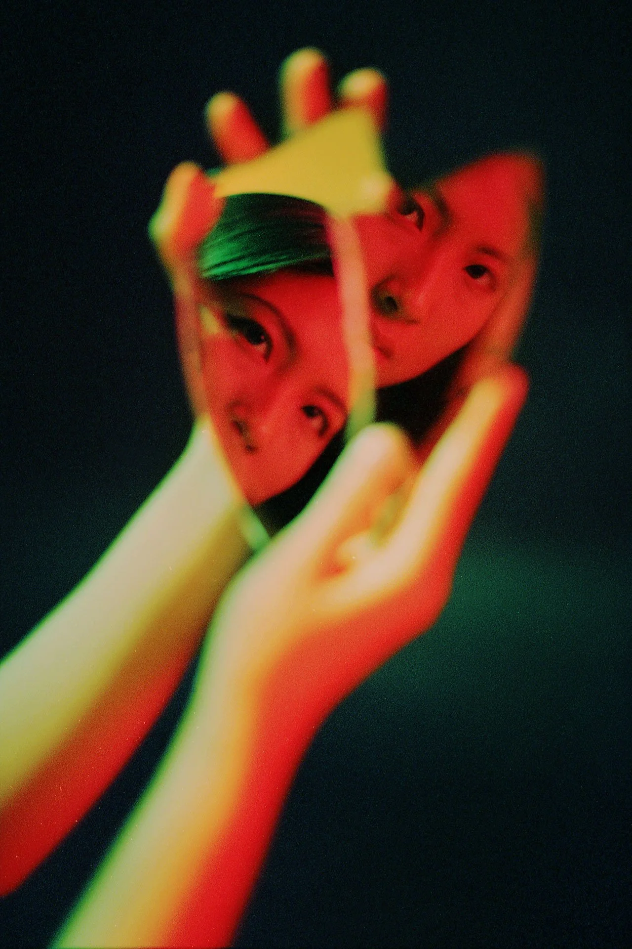 A hand holds a transparent object with multiple images of a woman's face embedded inside, creating a layered, surreal visual effect.